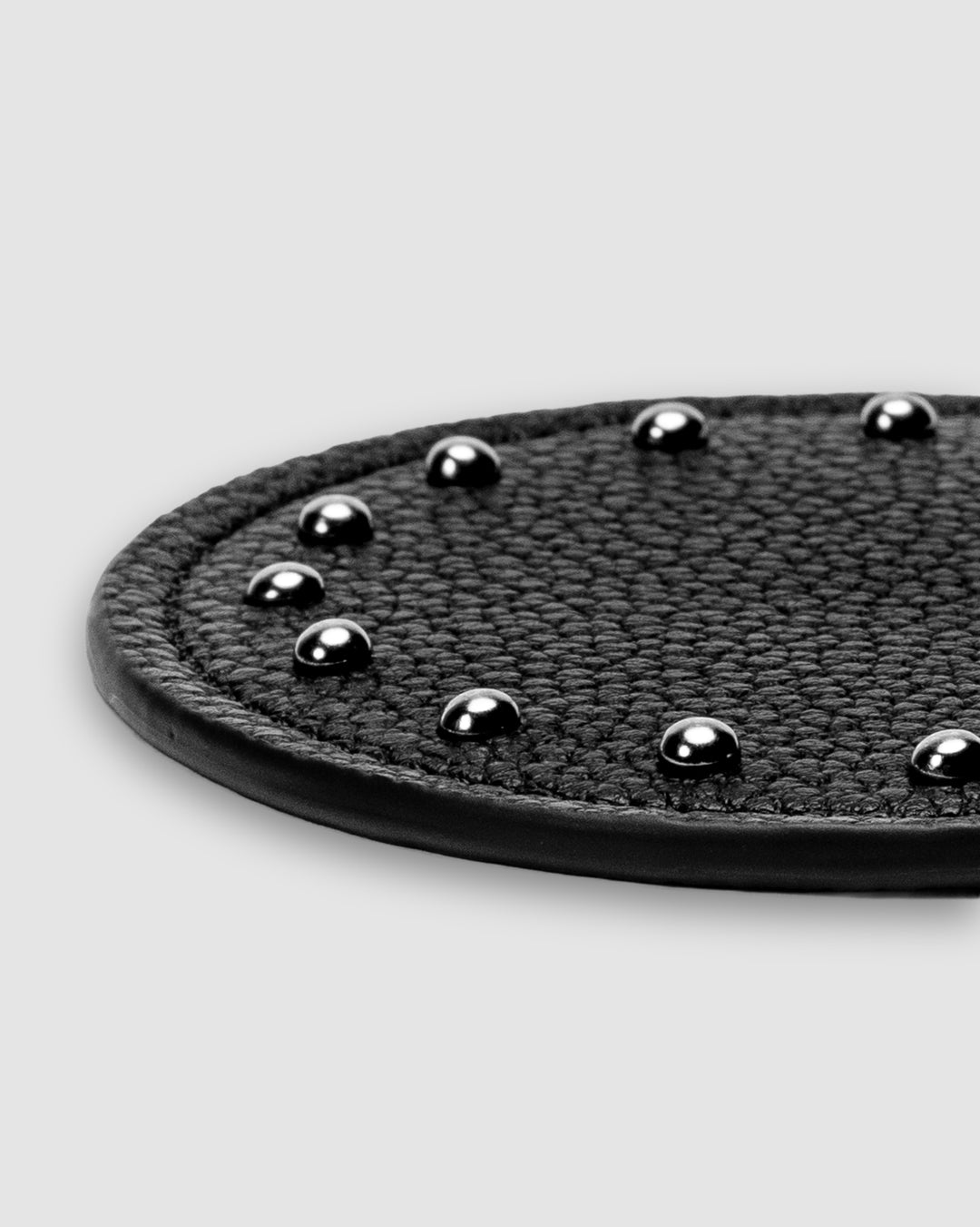 Close-up detail of silver dome studs and stitched edge on black recycled leather coaster — SERVIR hand-embellished hardware